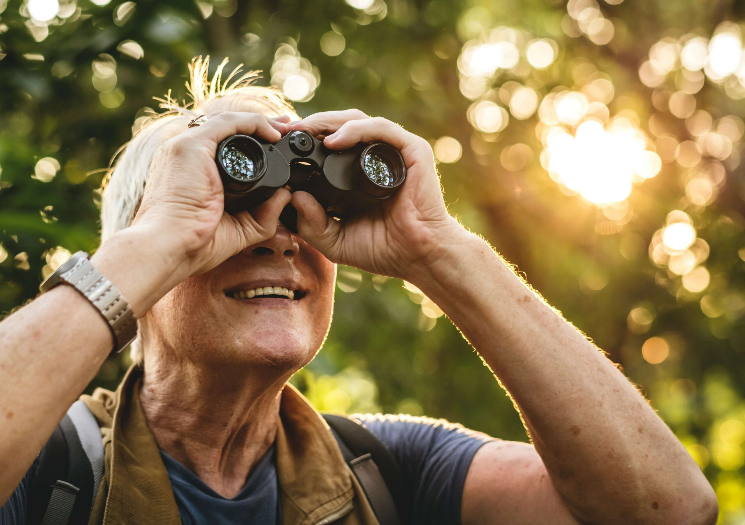 Close-up of hands holding birdwatching binoculars on a sunny morning